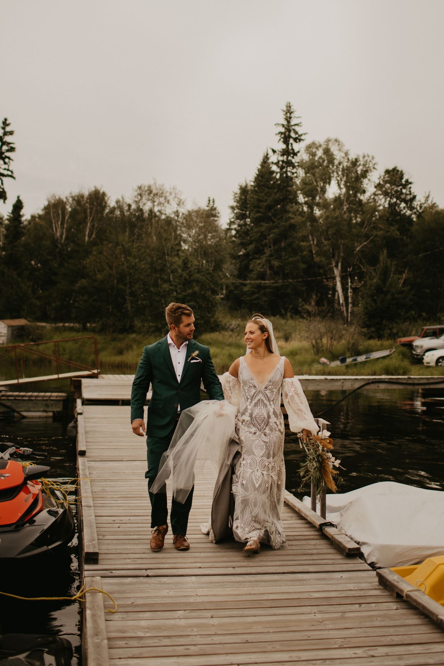Couple walking on wooden dock with seaplanes and boats in background.