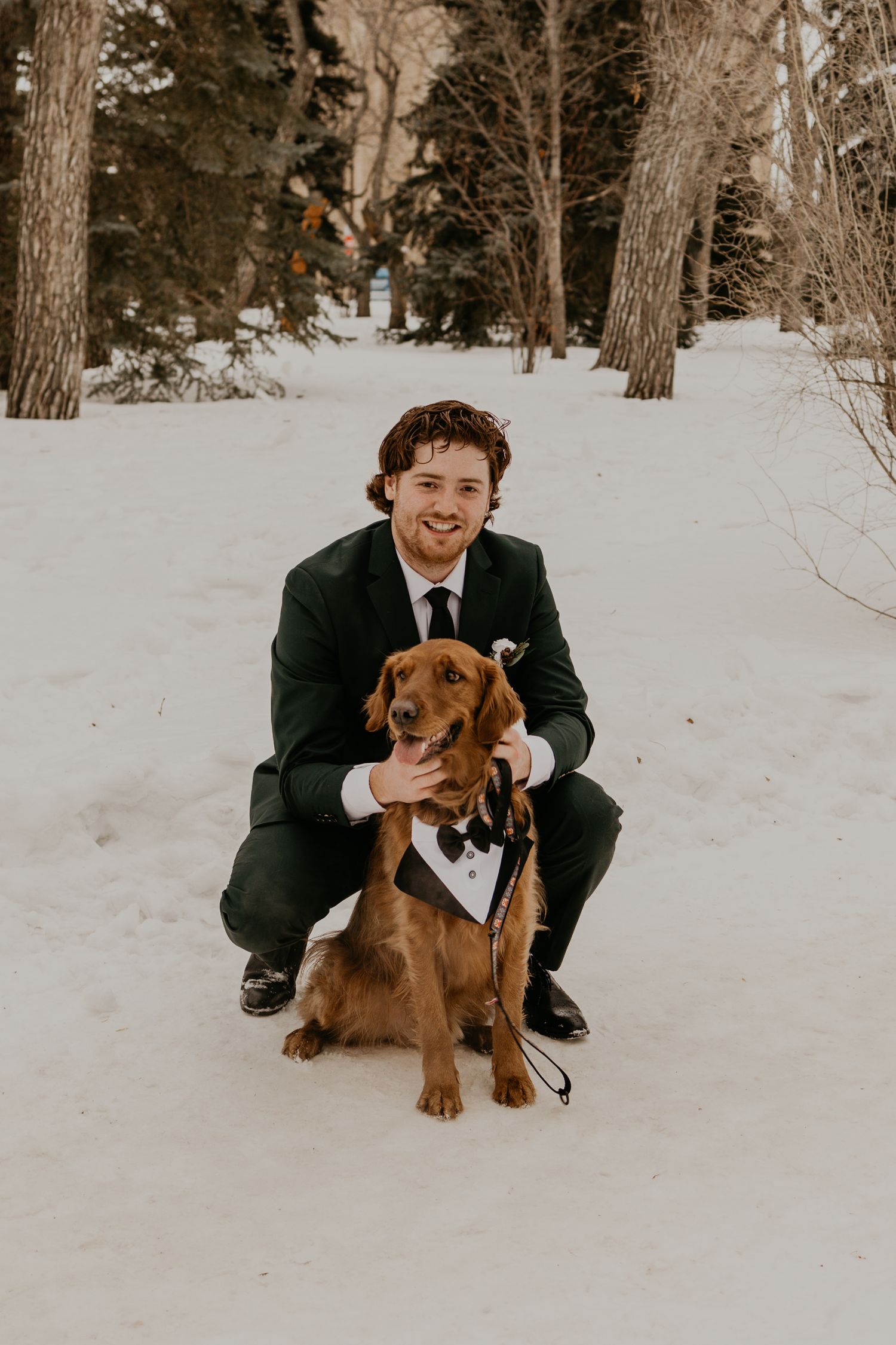 Wedding portrait in snow featuring a dressed dog with bow tie and their companion.