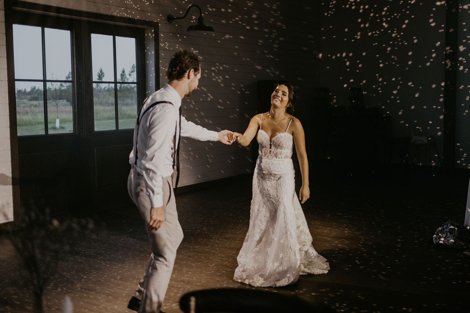 A couple dances in a sparkle-filled reception space with dramatic lighting.