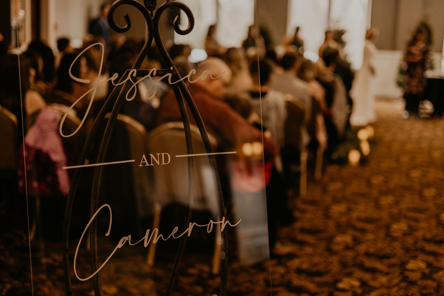 Artistic shot of wedding signage with cursive text through decorative glass.