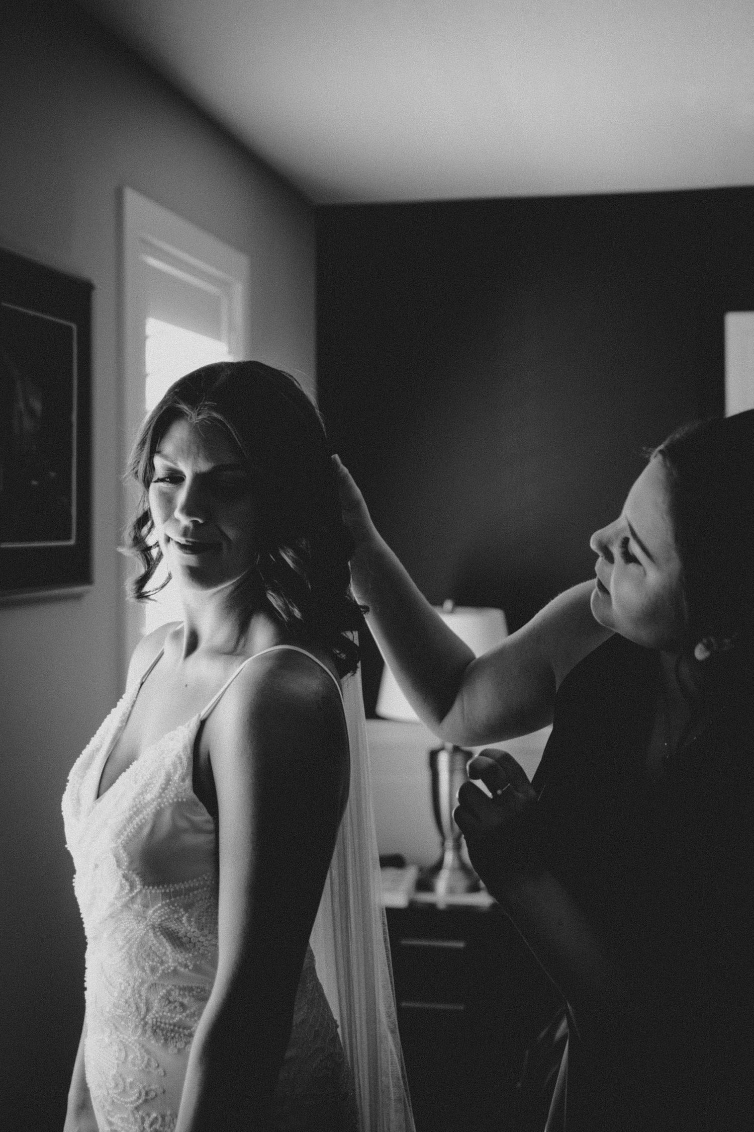 A black and white photo capturing final touches of wedding day preparations.