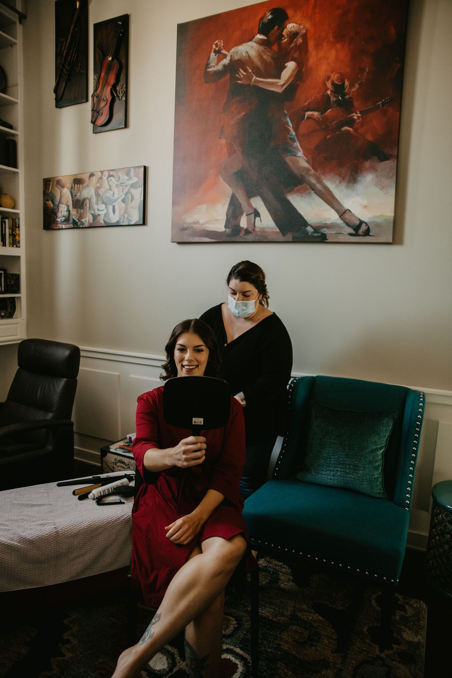 Two people sitting in front of a dramatic tango dance painting in a room with emerald green velvet chairs.