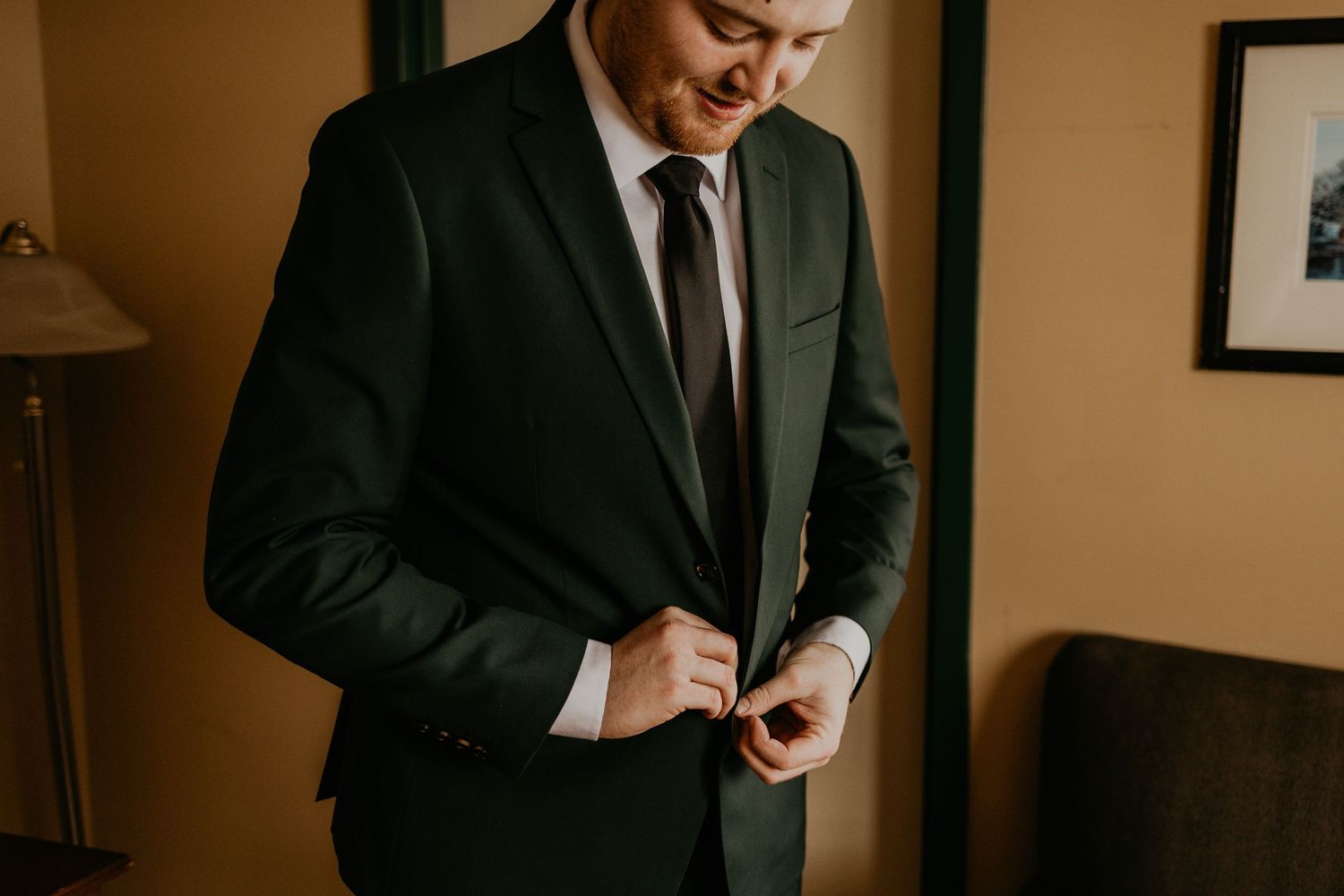 Close-up of hands adjusting buttons on a dark formal suit jacket.