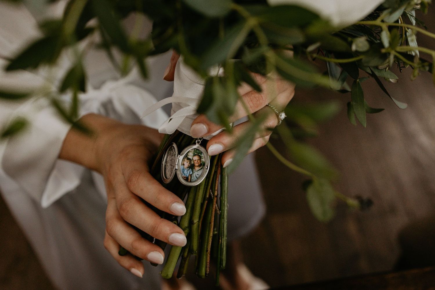 Hands holding a bouquet wrapped with a decorative pendant.