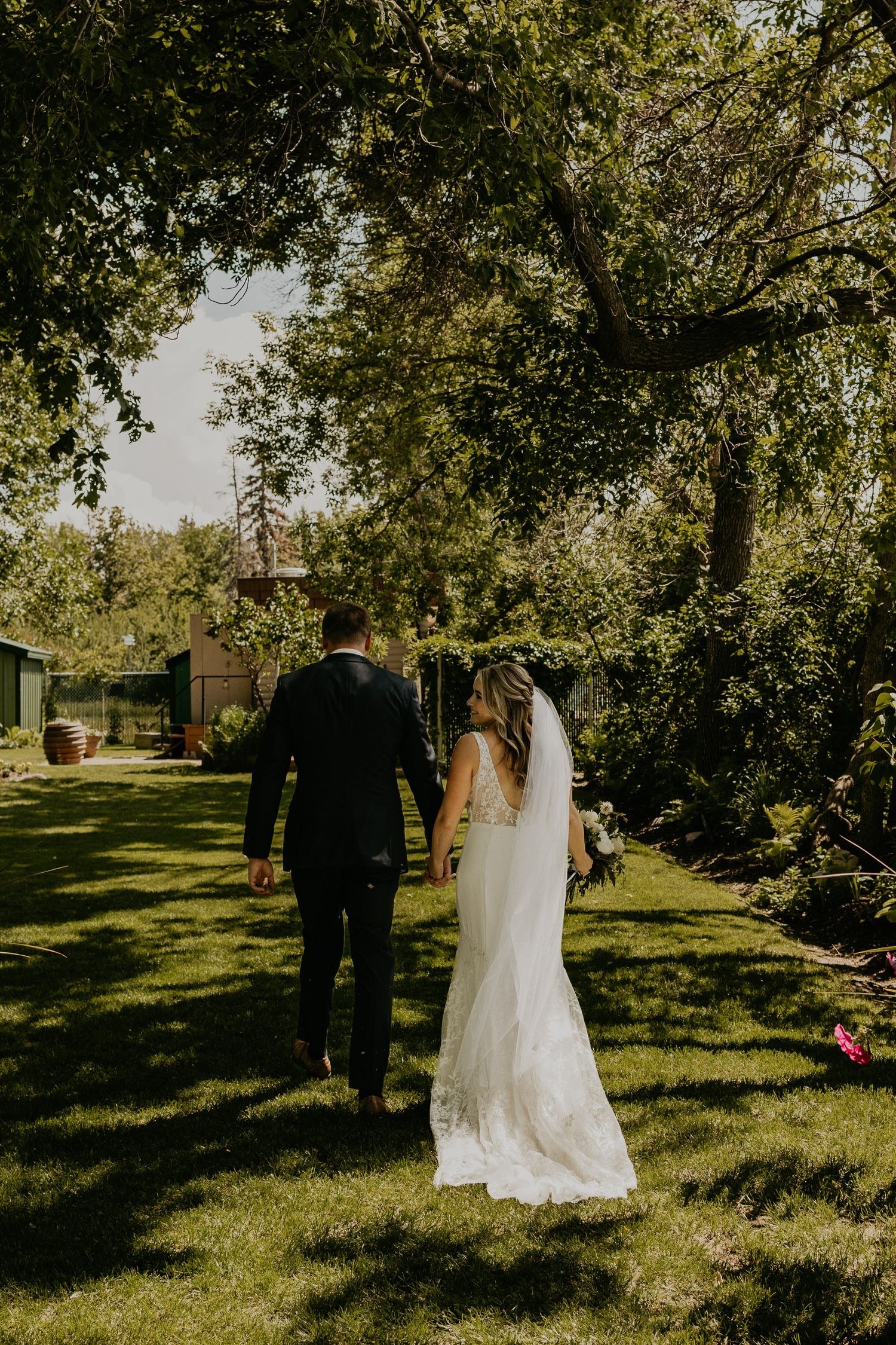 Newlyweds walking together through a lush garden setting on their wedding day.