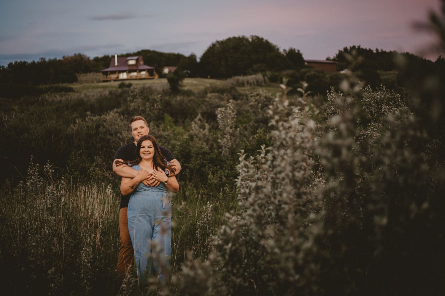 A couple embracing in a wildflower field during golden hour.
