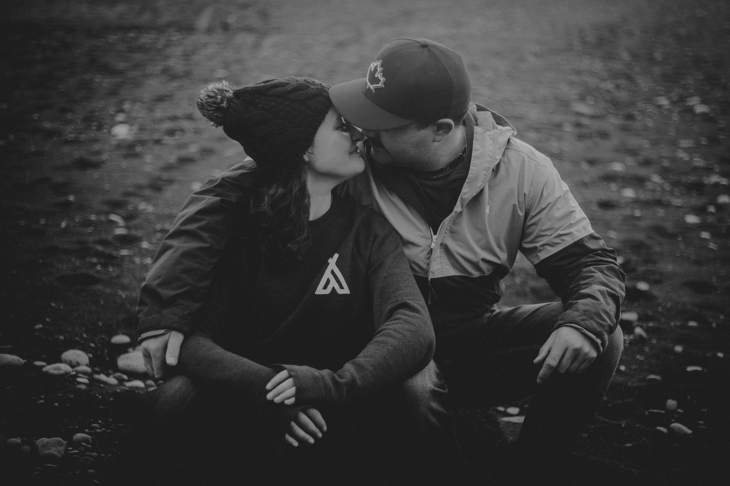 Black and white intimate portrait of a couple sitting together on fallen leaves.