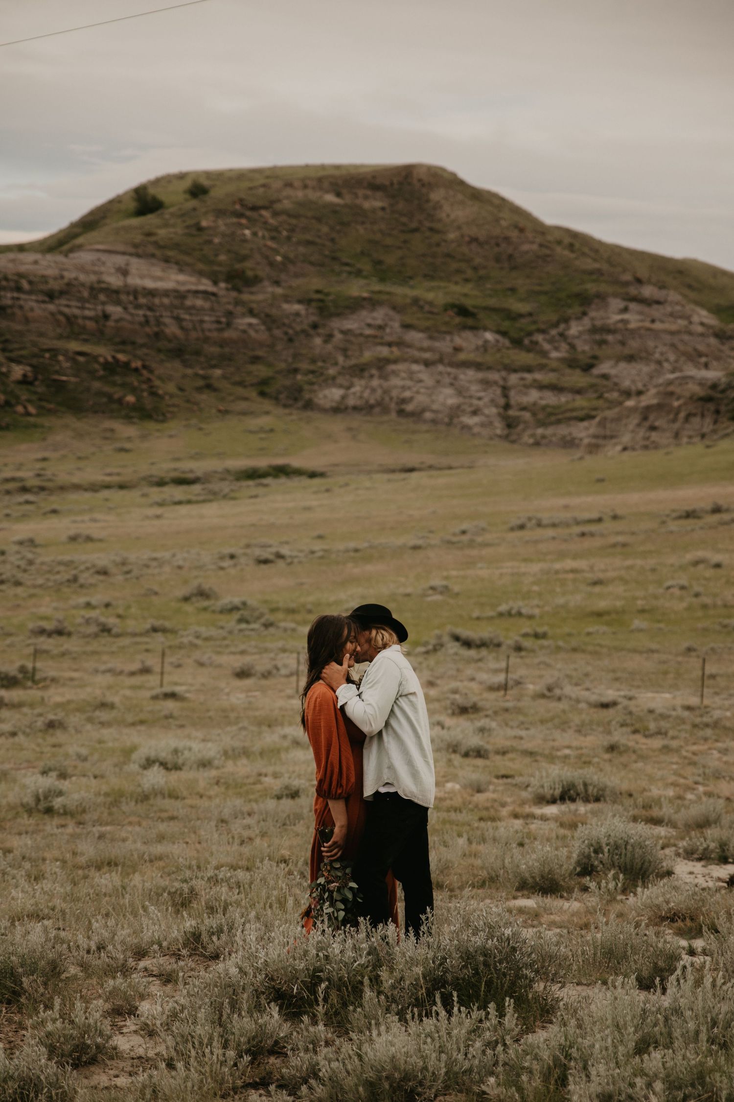 A romantic moment captured in a sweeping desert landscape with dramatic rock formations.