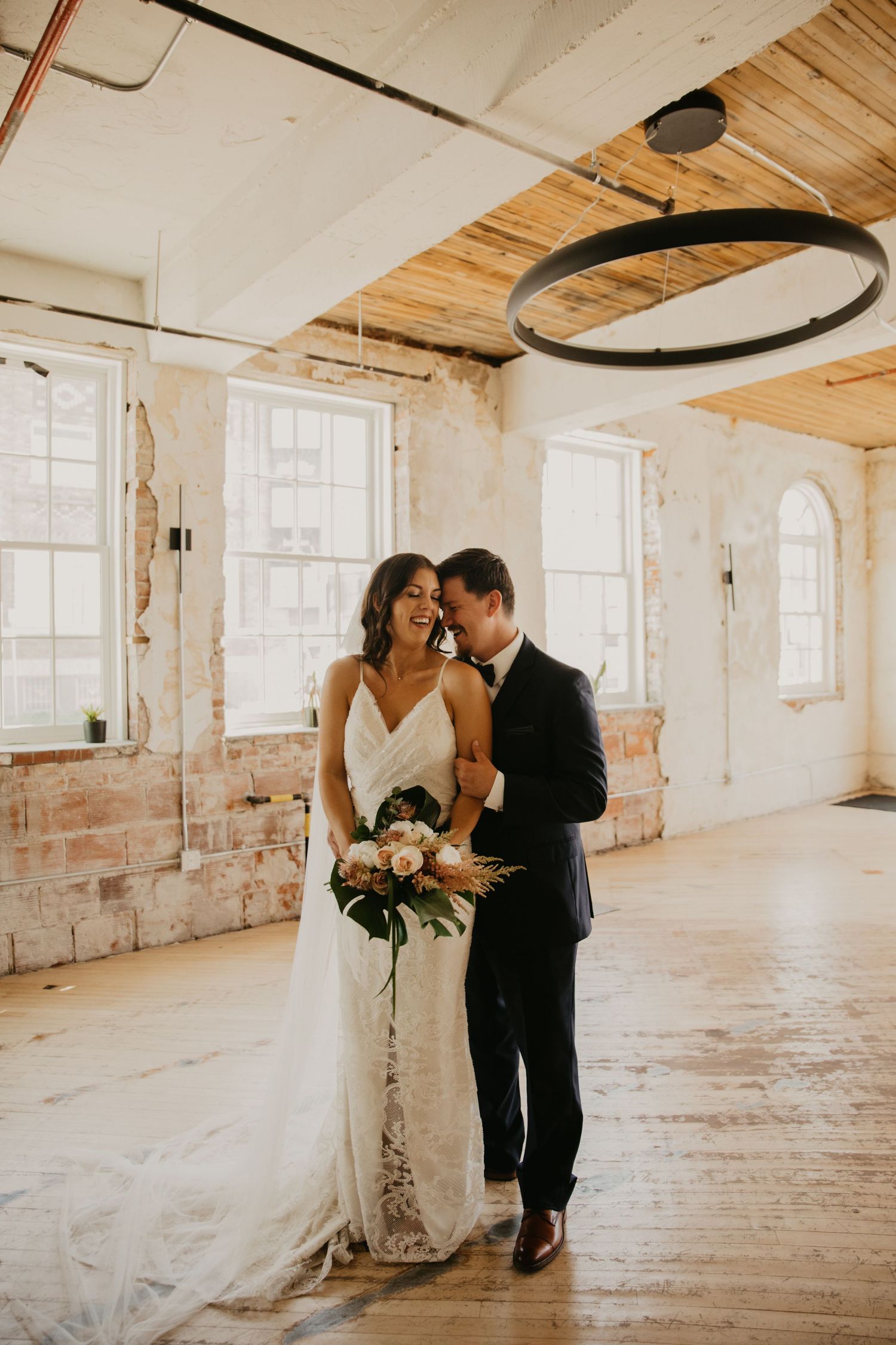 A tender wedding moment captured in an industrial-chic venue with exposed brick walls.
