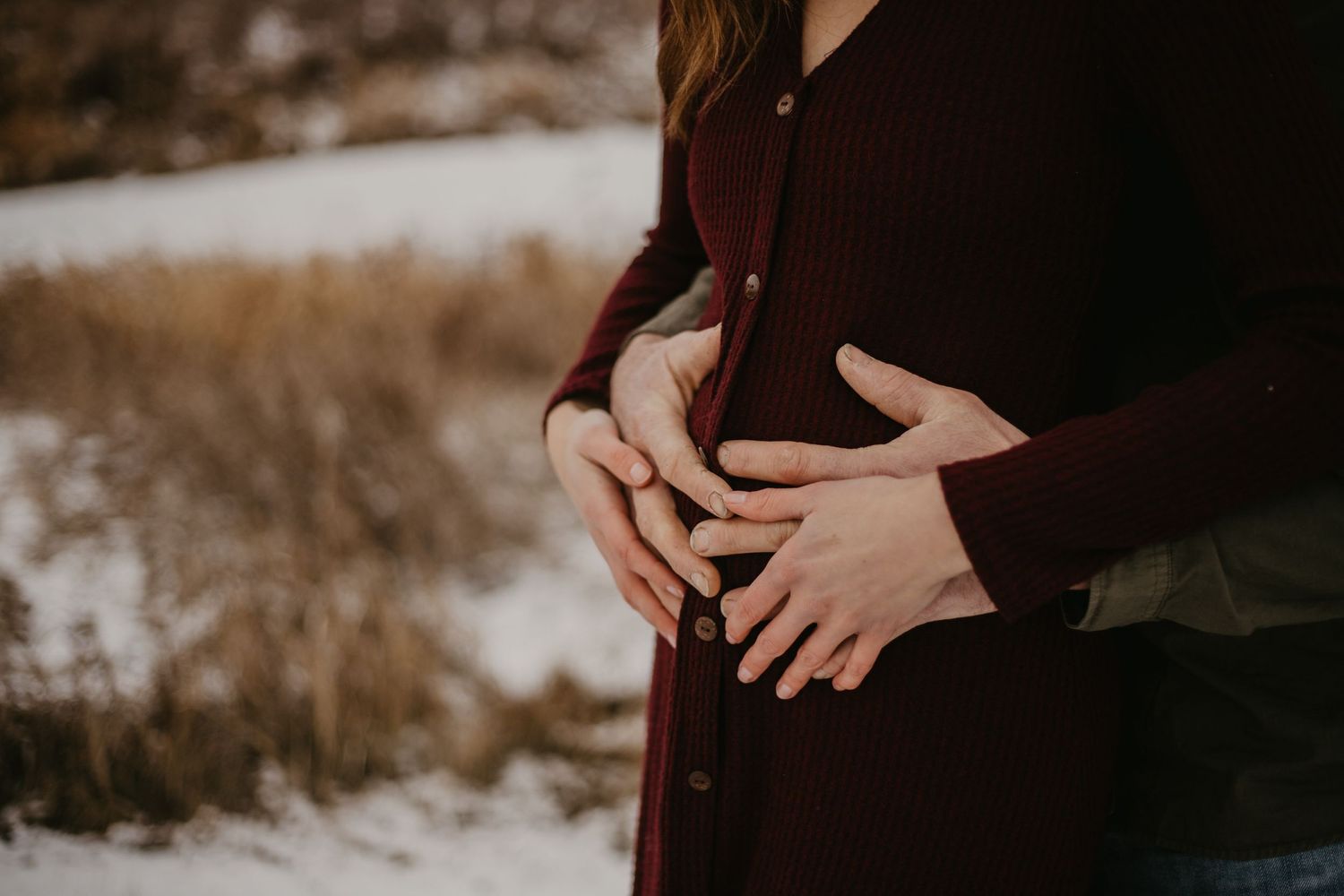 Close-up shot of hands gently resting on a burgundy sweater.