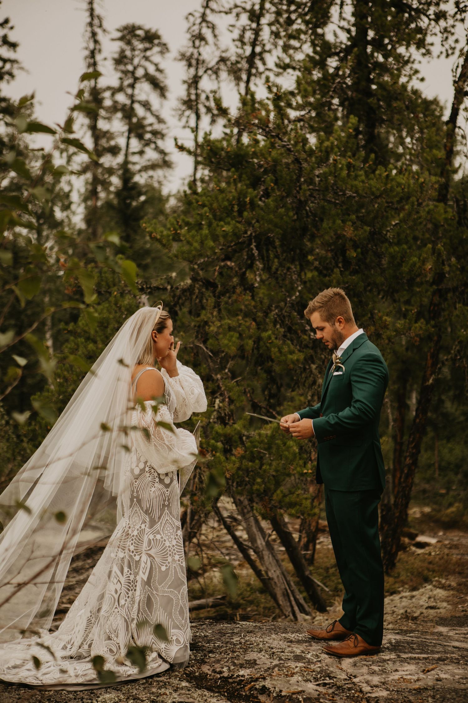 Wedding couple reading vows on natural stone platform with forest backdrop.