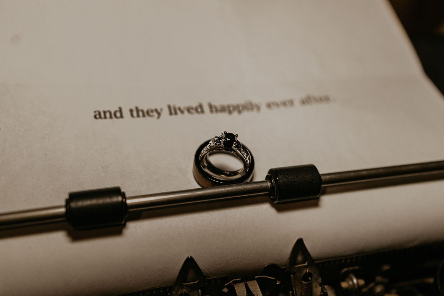 A wedding ring placed on a vintage typewriter displaying 'and they lived happily ever after' text.