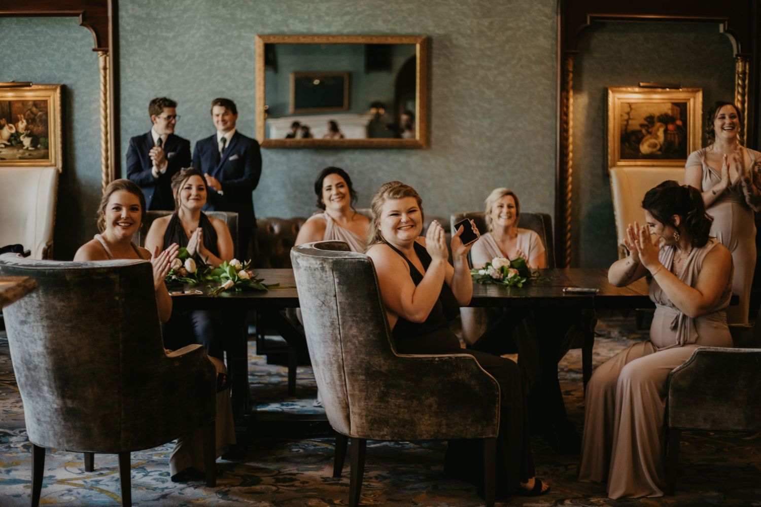Wedding guests react emotionally while seated in upholstered chairs during an indoor ceremony.
