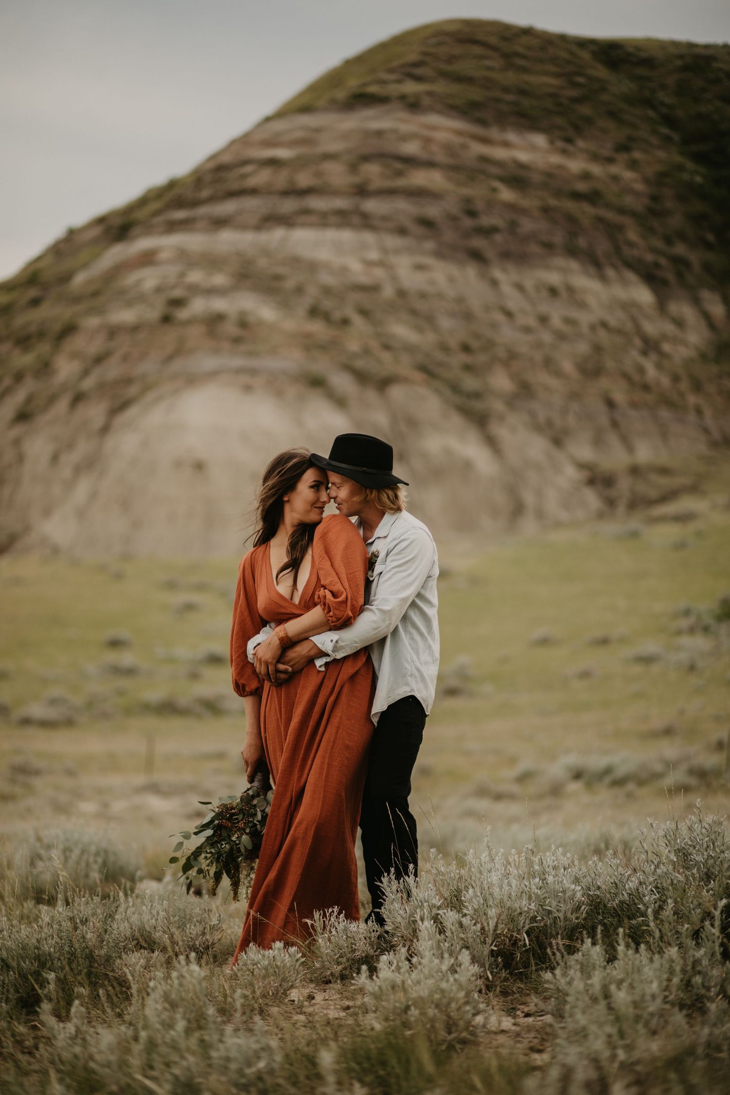 An intimate moment captured between a couple against a striking desert landscape.