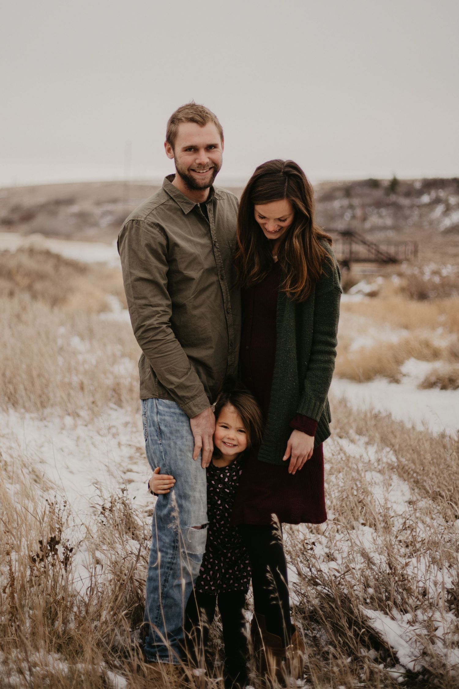 Family portrait in casual attire against a winter landscape backdrop.