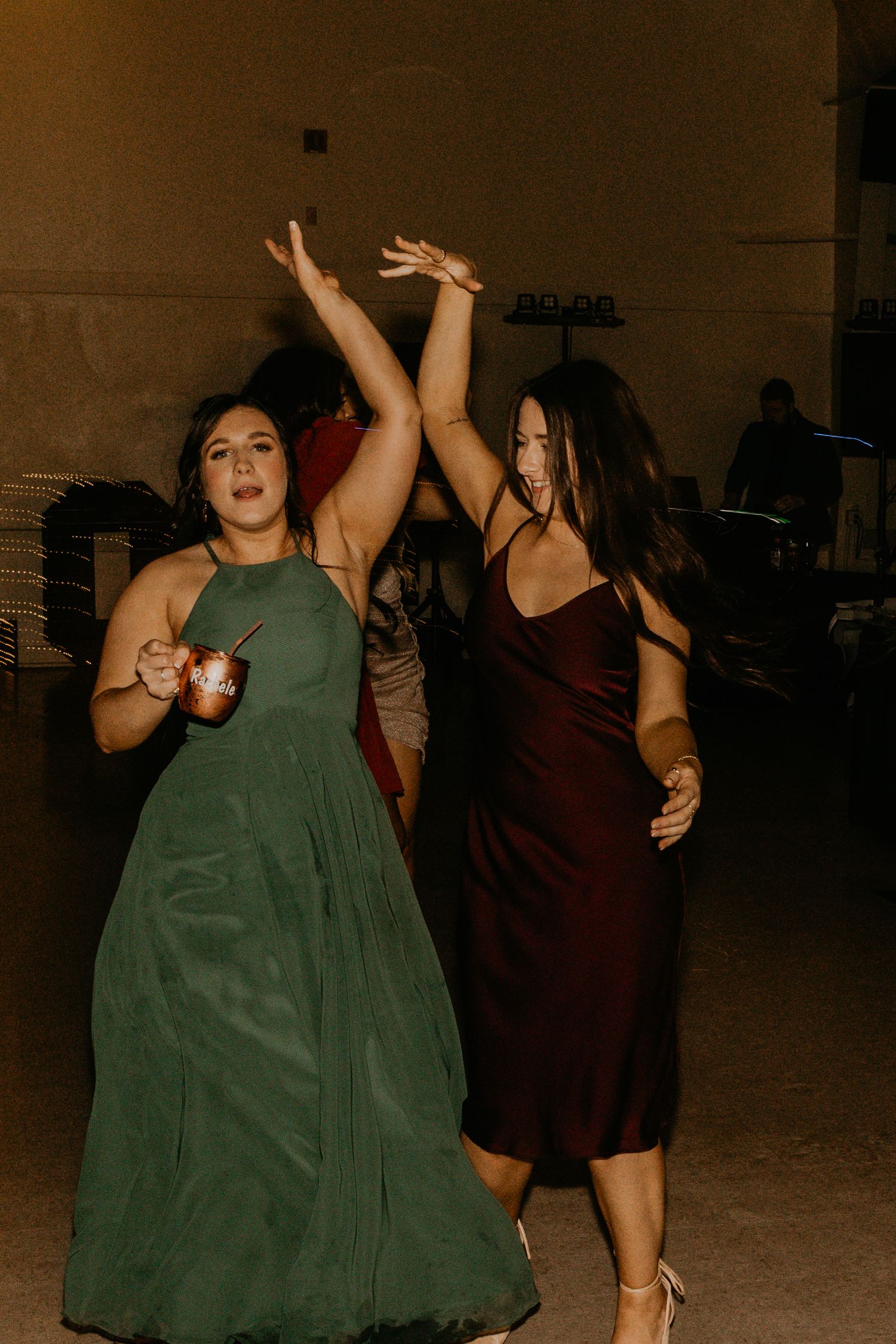 Dancing wedding guests in elegant dresses enjoying a reception celebration.