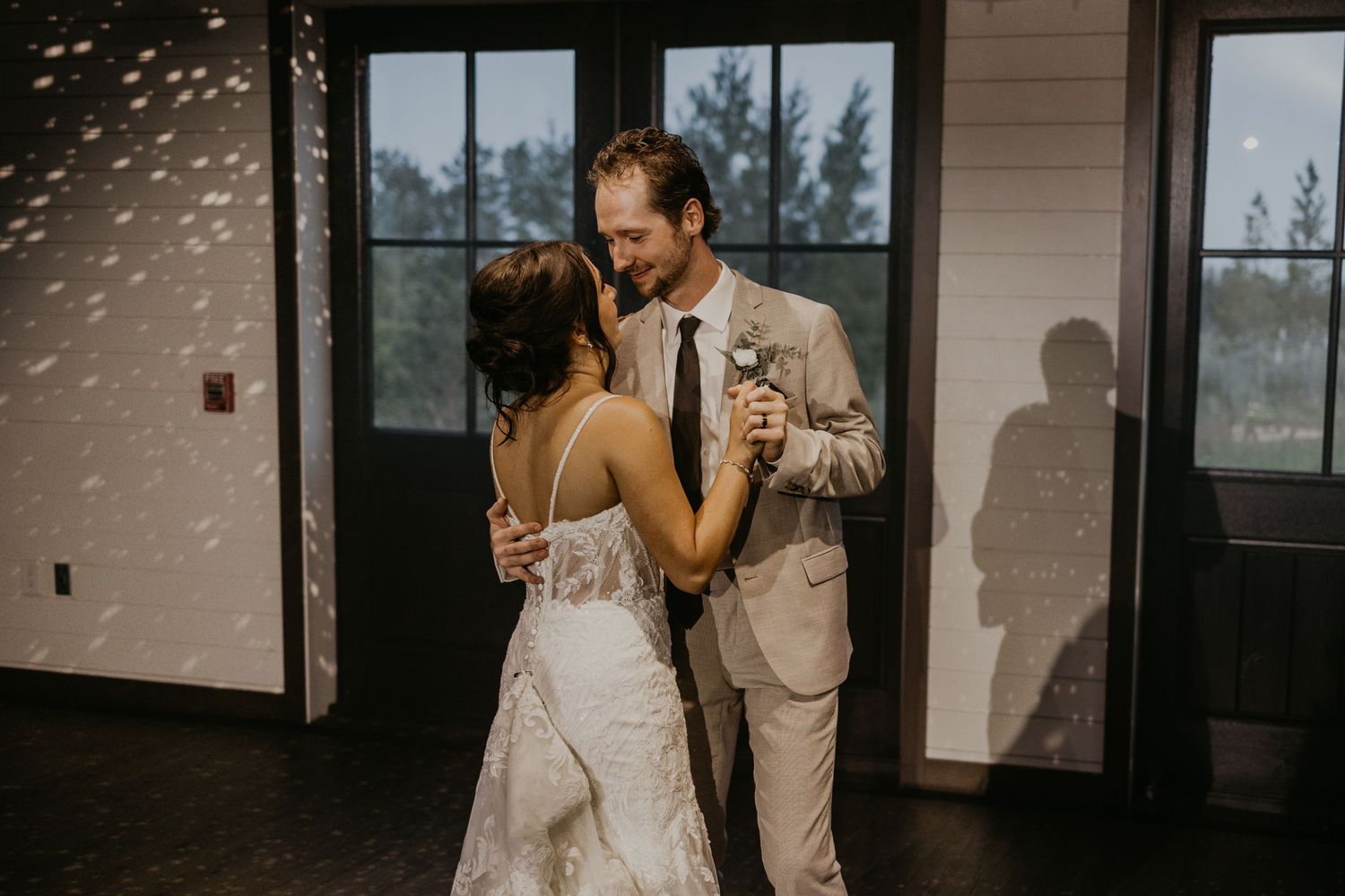 A couple shares their first dance in formal attire inside a reception venue.