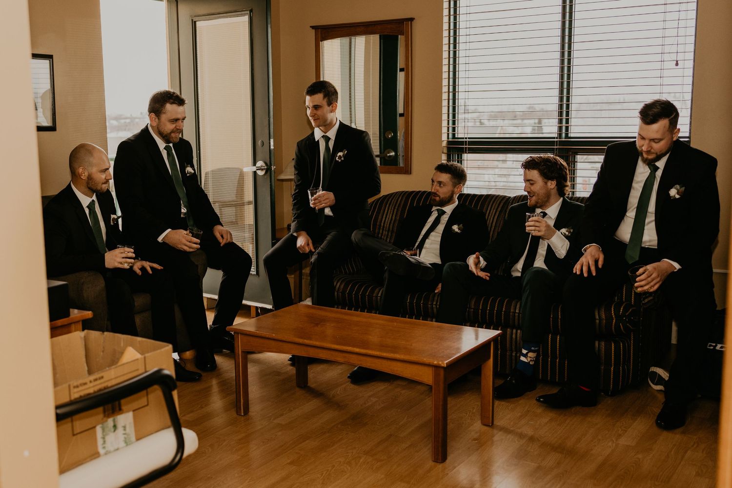 Groomsmen in matching suits toasting with drinks before the ceremony.