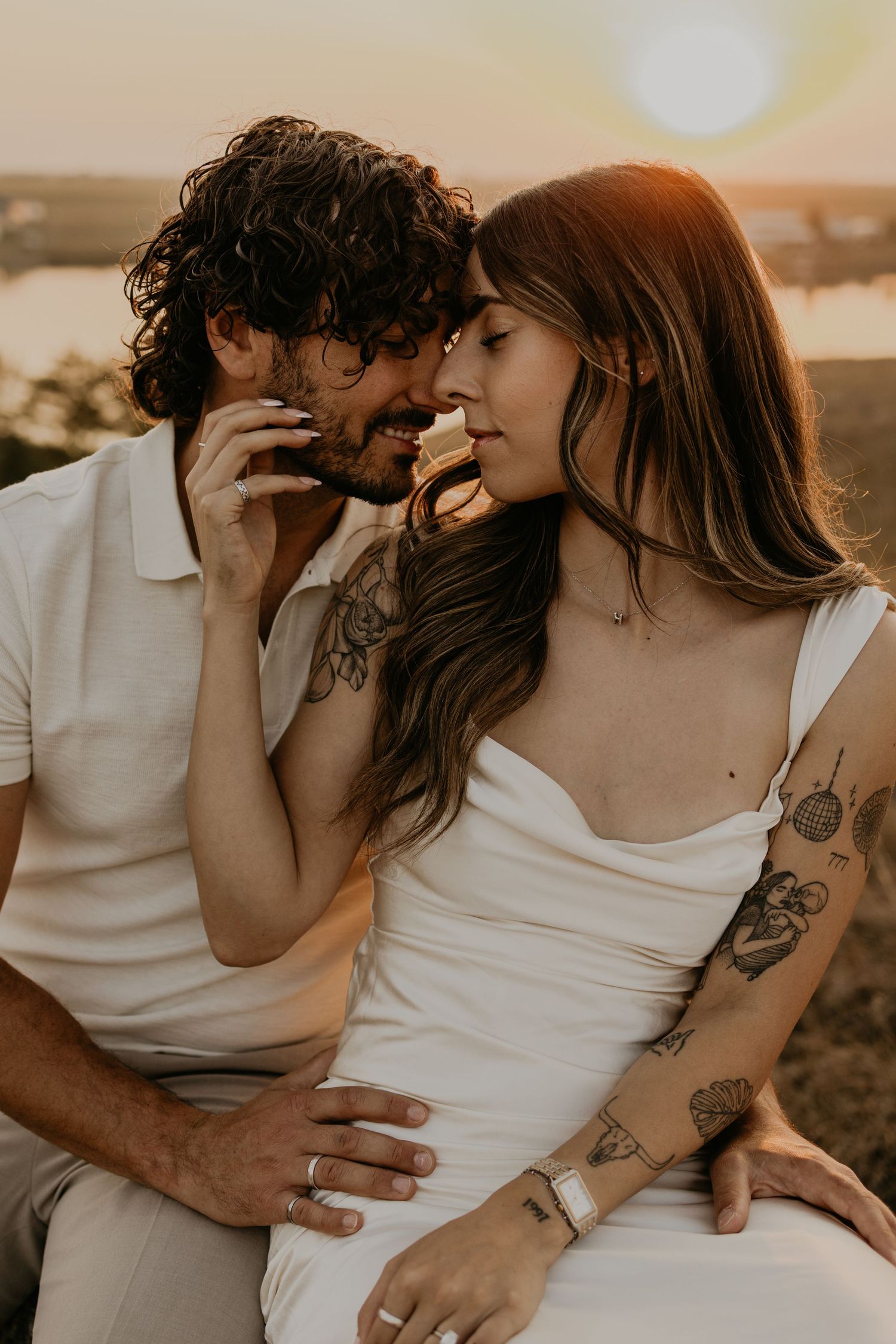 Intimate close-up of couple in white attire during sunset photoshoot.