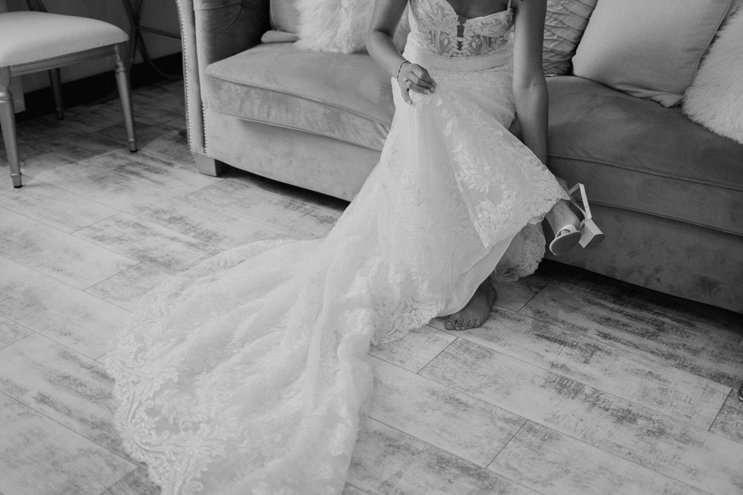 Black and white detail shot of a wedding dress train on wooden flooring.