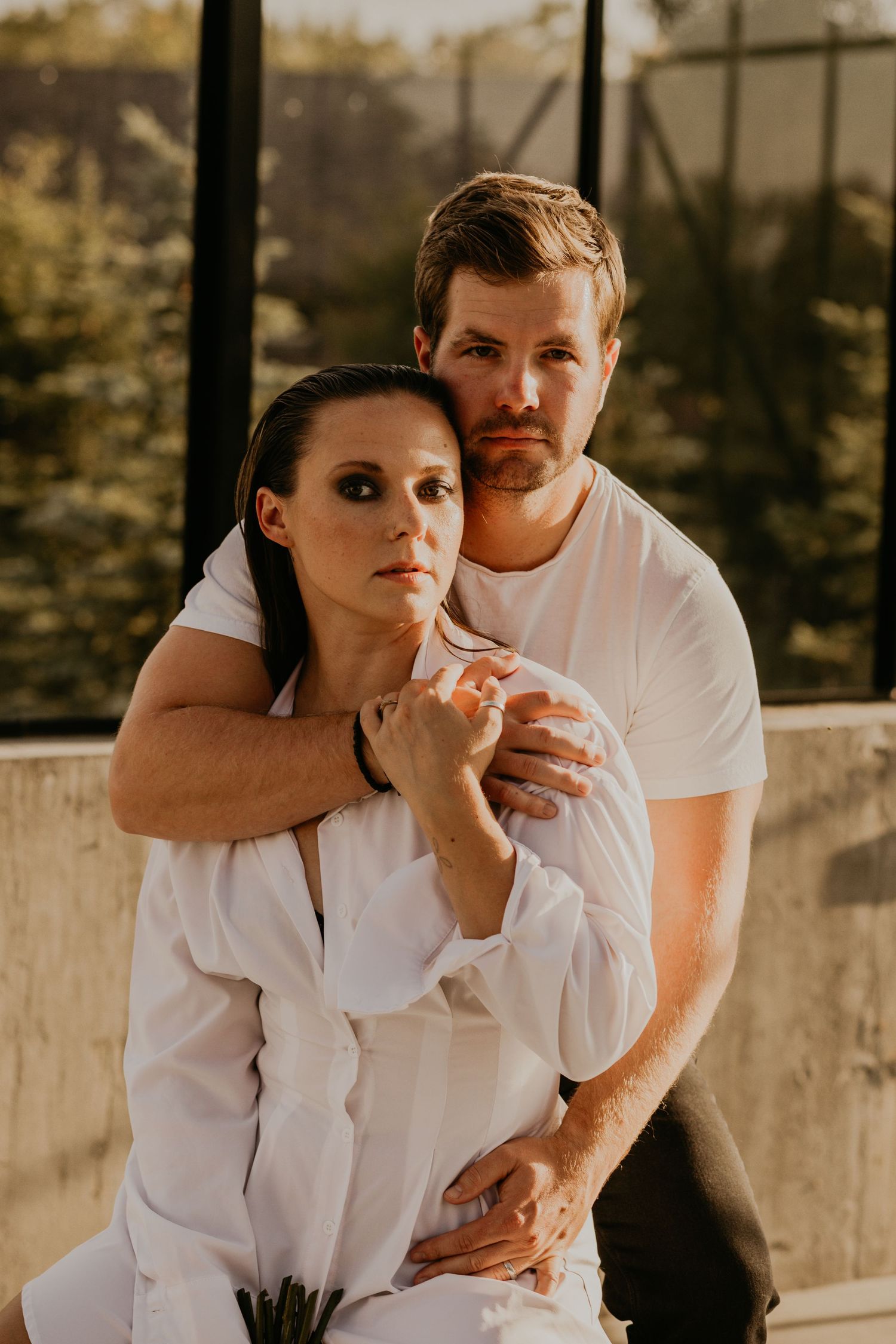 An intimate portrait of a couple embracing in white clothing during golden hour.