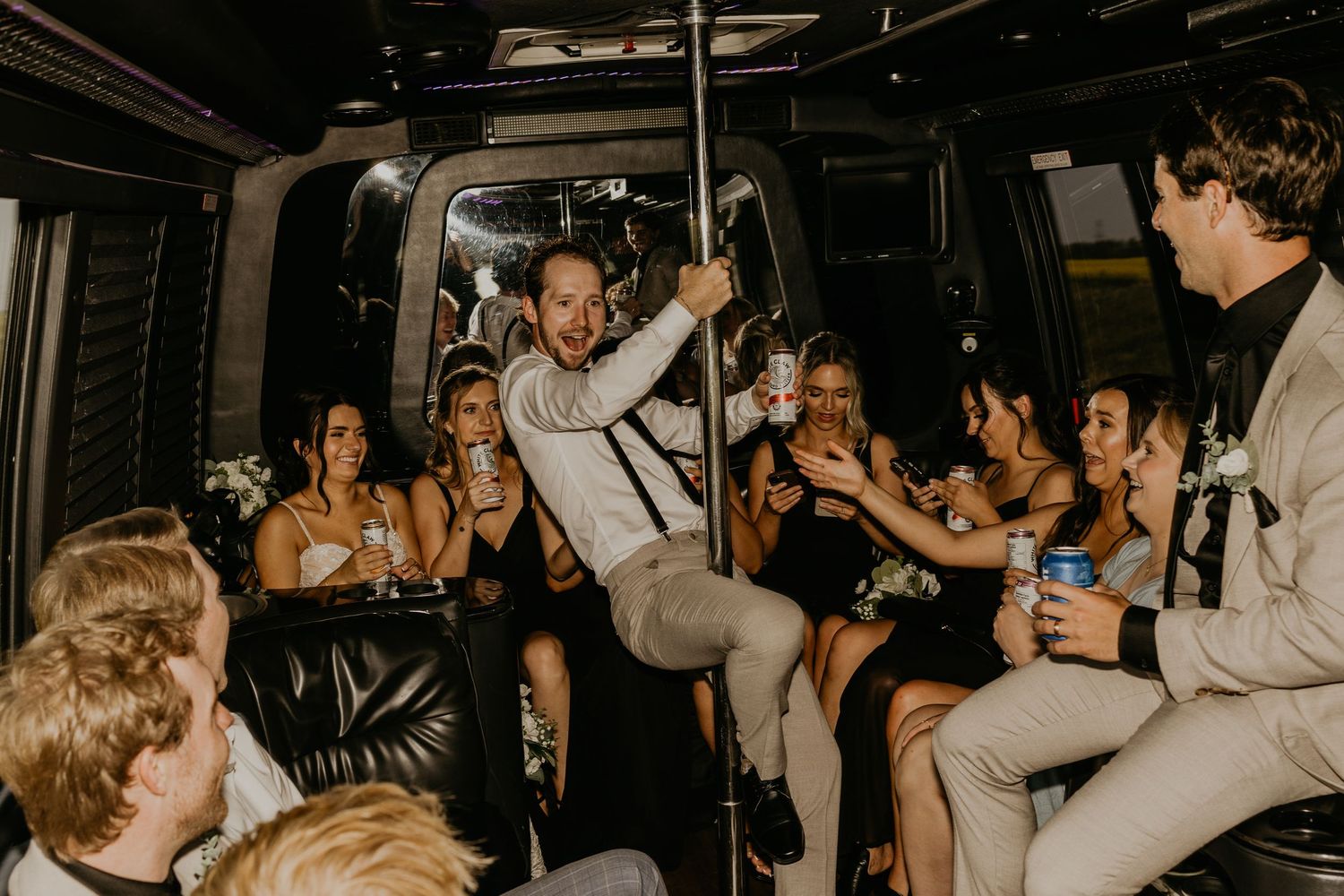Wedding party celebrates inside party bus with dancing and drinks.