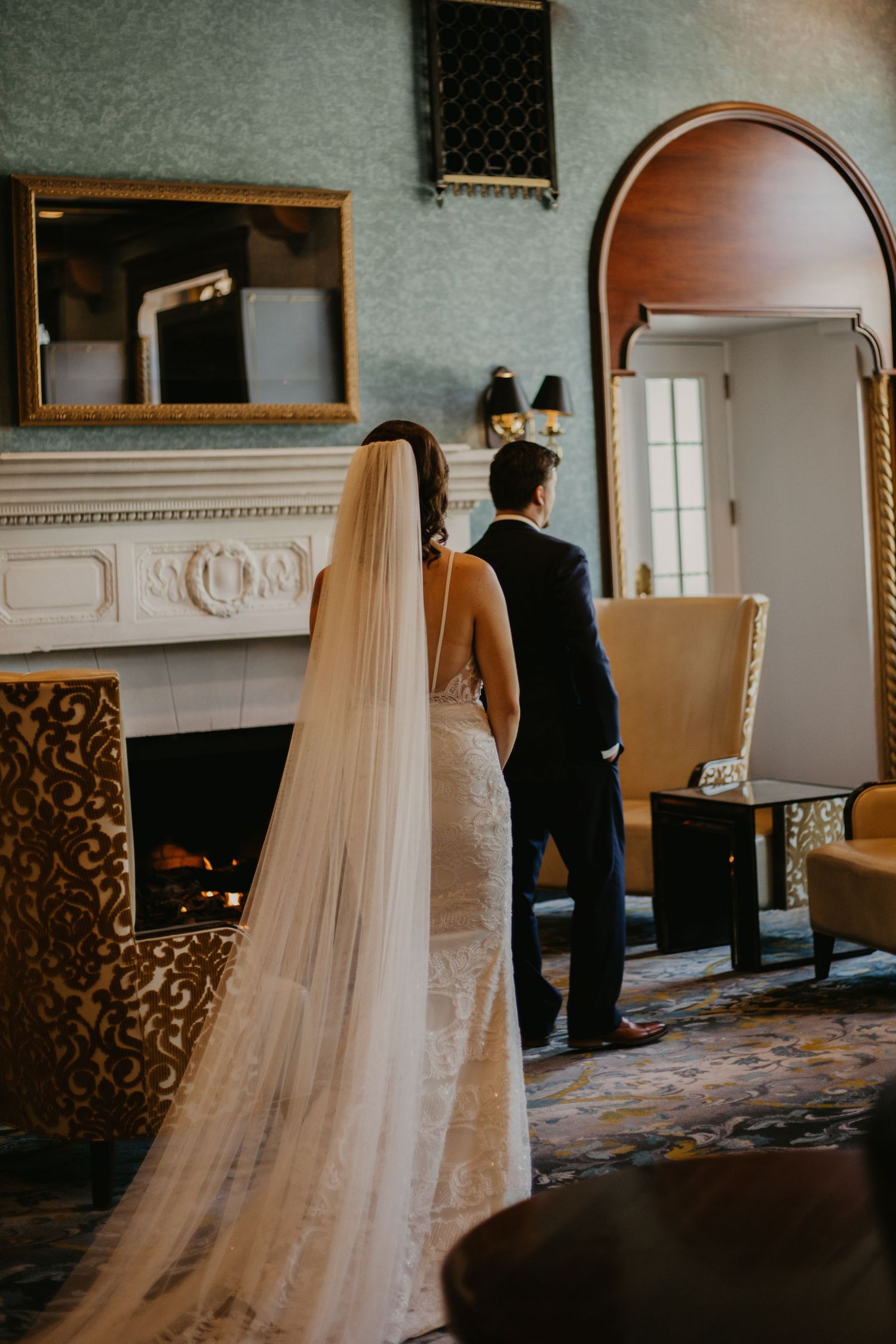 A dramatic silhouette of a bride's flowing veil against an elegant interior with fireplace.