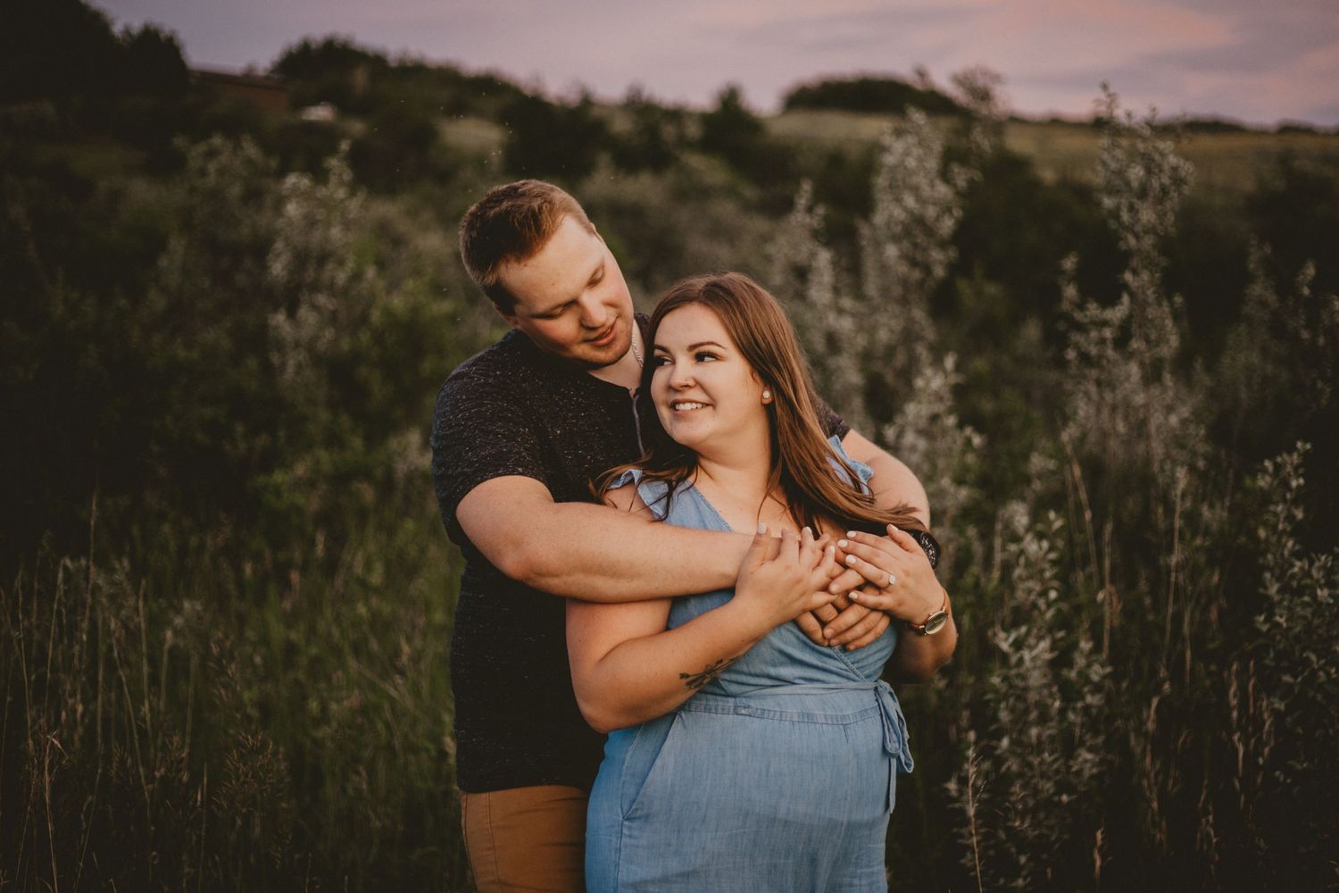 A couple sharing a joyful moment in a field at sunset.