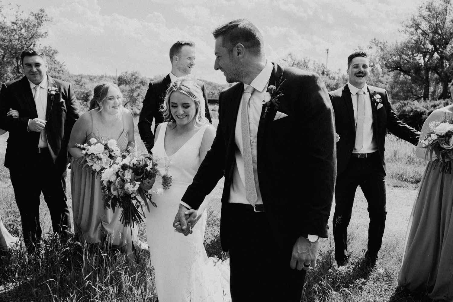 A black and white photo of a wedding party walking together outdoors.