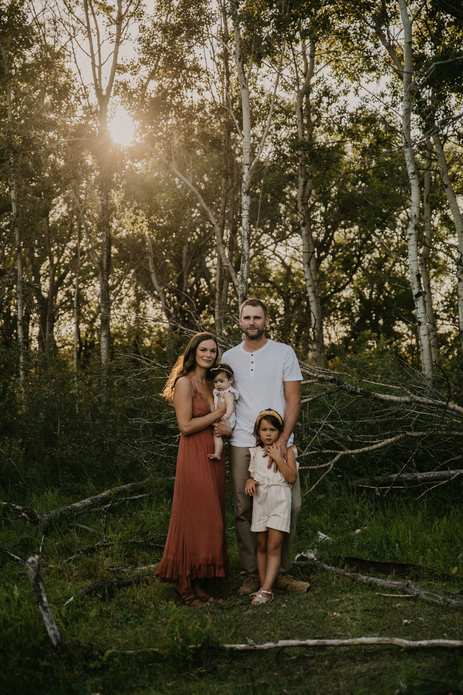 Family portrait in forest setting with sunlight streaming through birch trees.