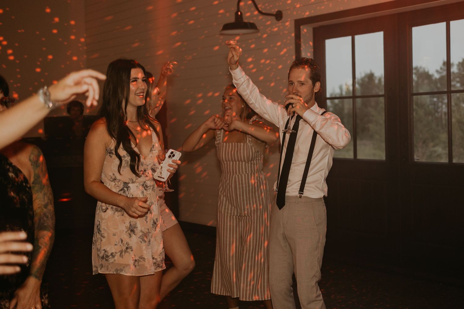 Wedding party guests dancing and celebrating with festive lighting.