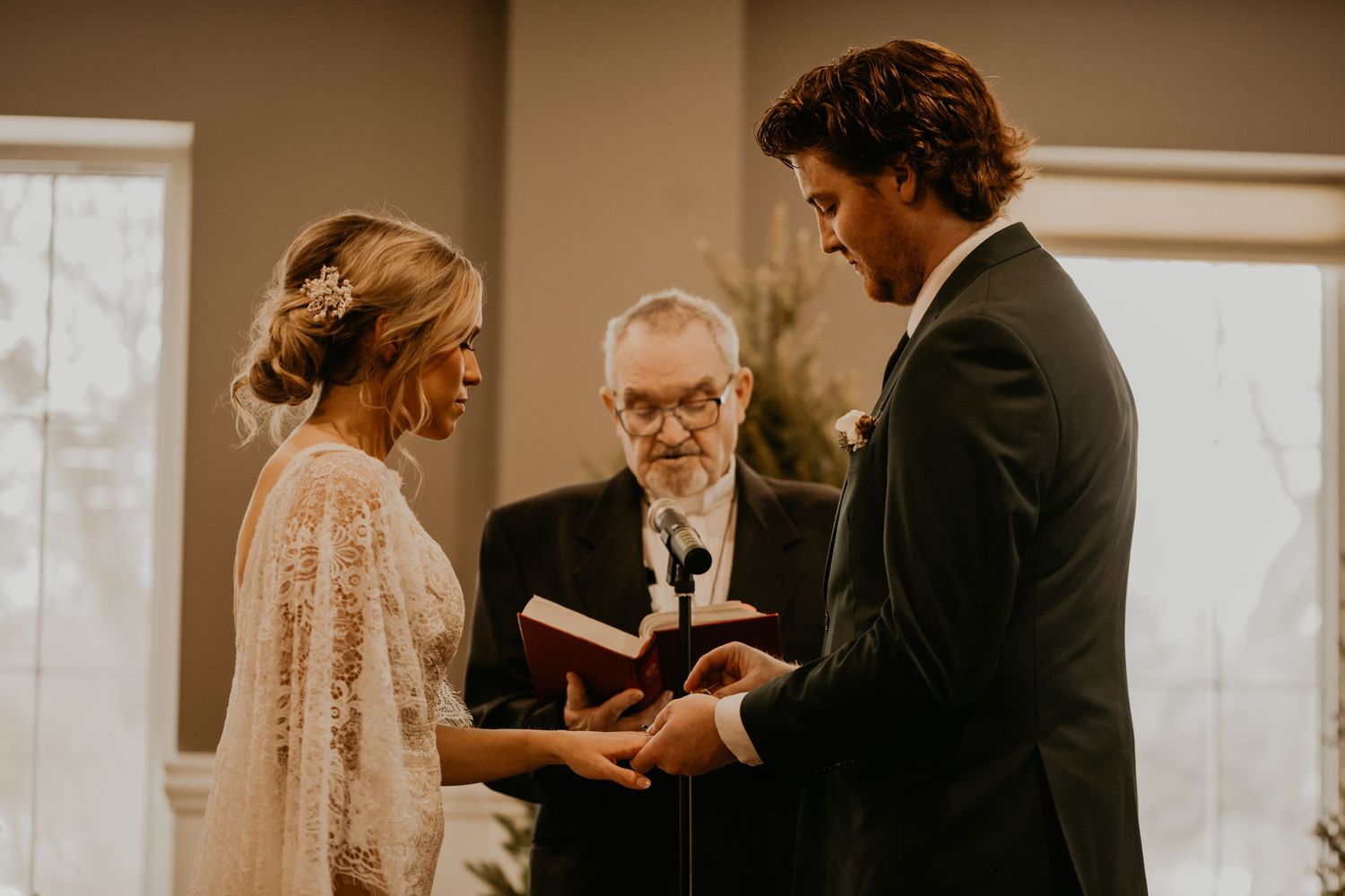Wedding ceremony in progress with an officiant conducting the service in a warm indoor setting.