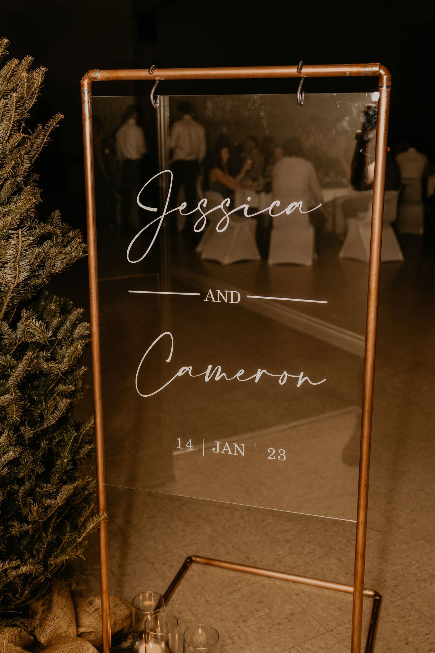 Elegant acrylic wedding sign with copper frame displaying 'Jessica and Cameron - 14 Jan 23'.