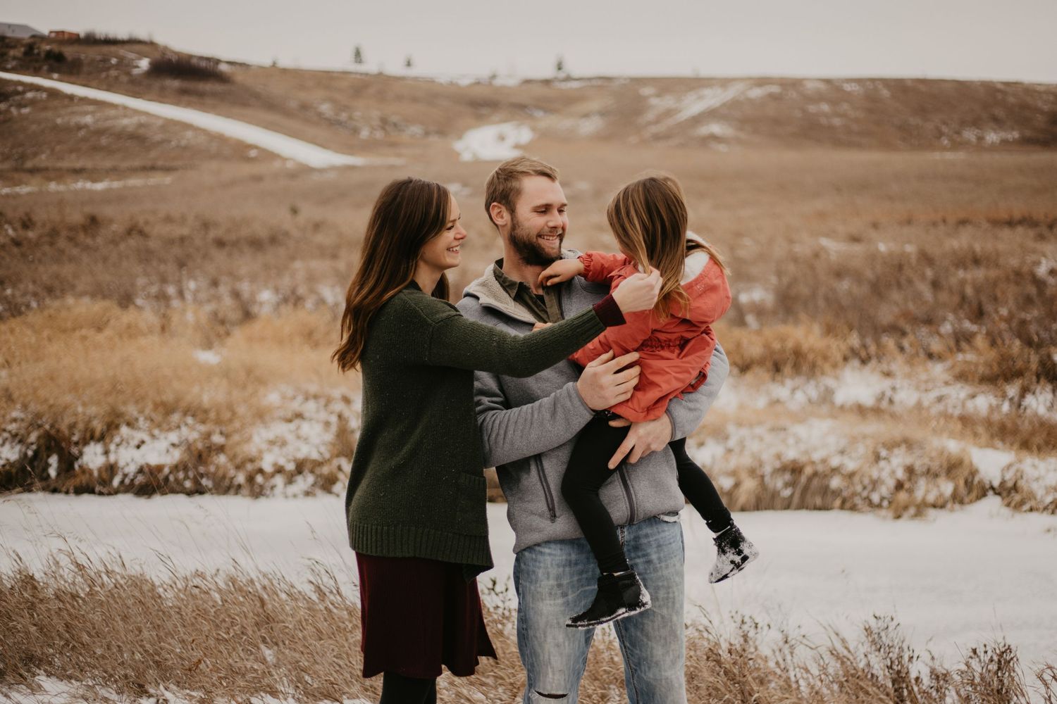 A heartwarming family moment captured outdoors in a winter landscape with rolling hills.