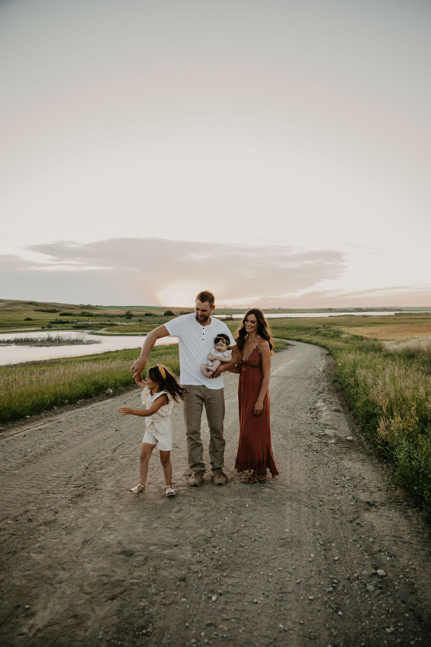 A joyful family plays together on a rural road during golden hour.