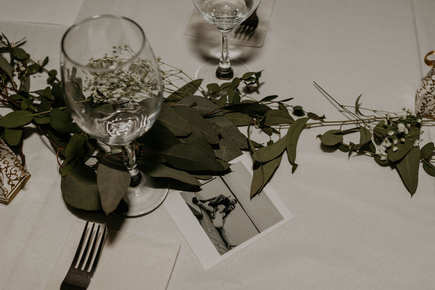Wedding table setting with crystal glasses and delicate greenery garland decoration.