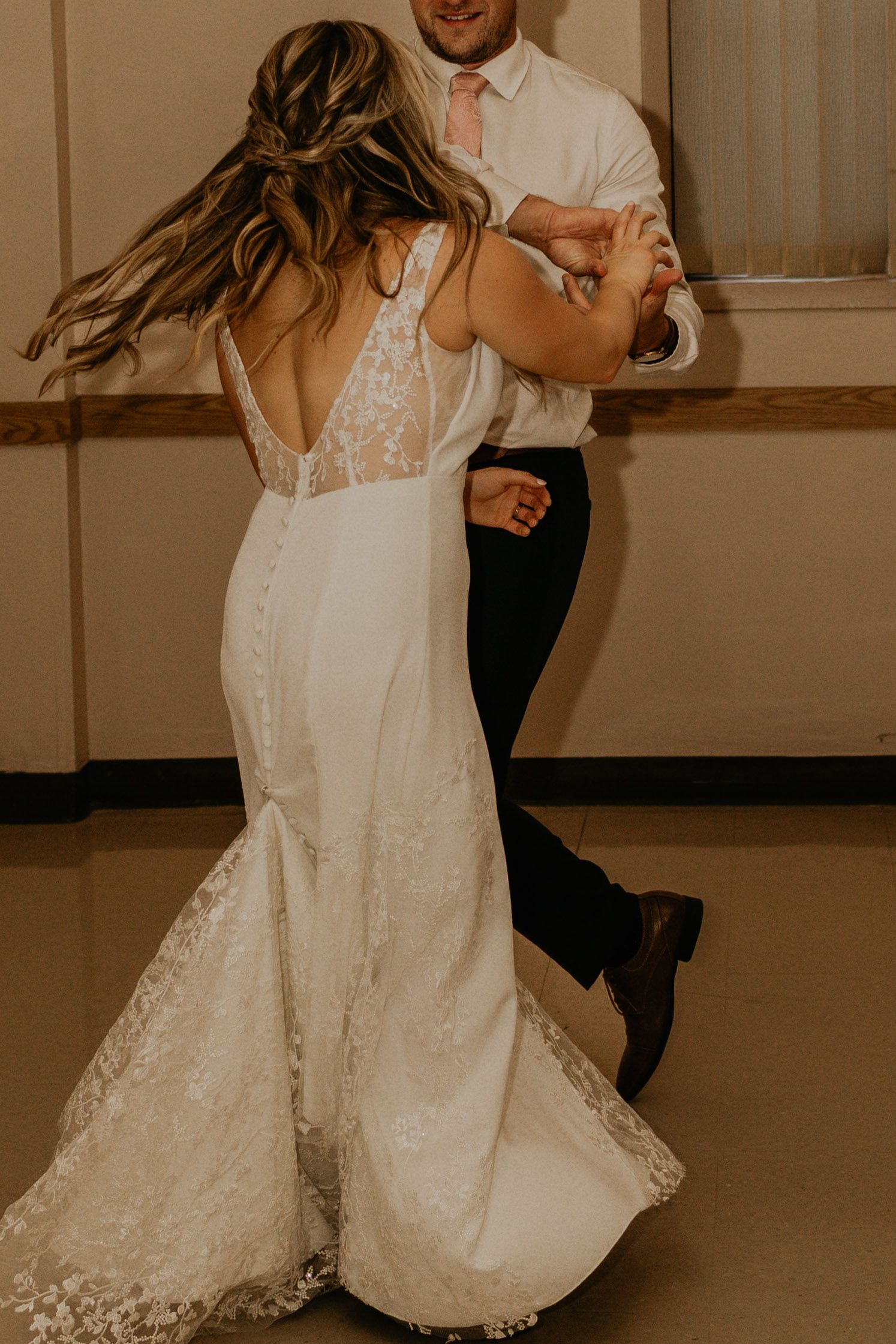 Elegant wedding dance with bride in lace detailed gown twirling on dance floor.