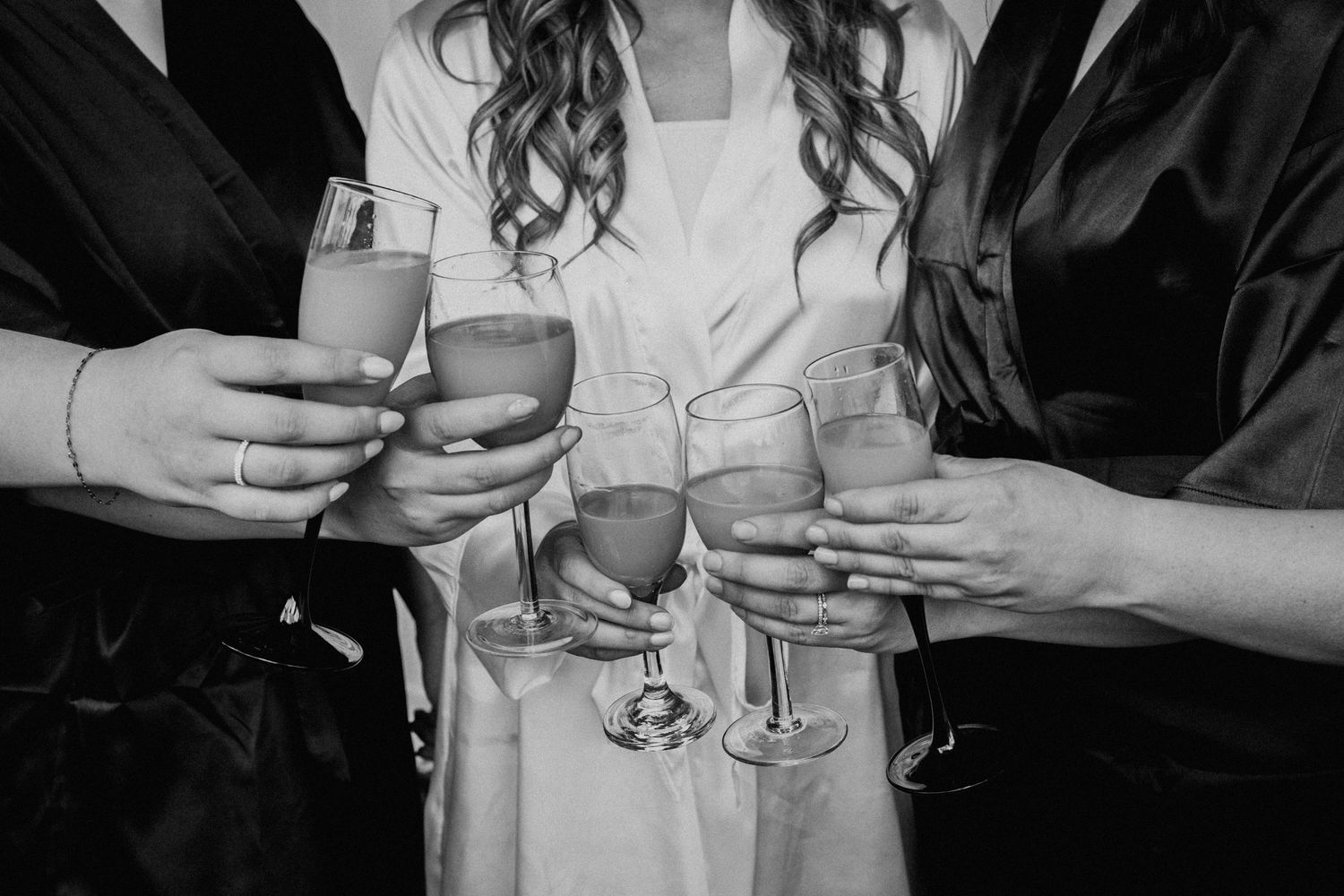 Close-up shot of champagne glasses being toasted between people wearing black and white robes.