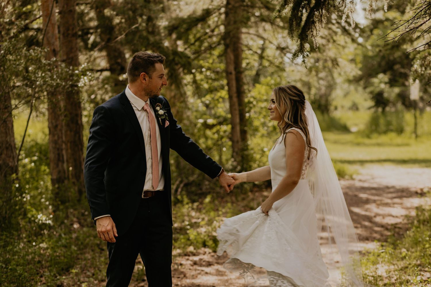 A couple shares a tender moment on their wedding day along a tree-lined path.