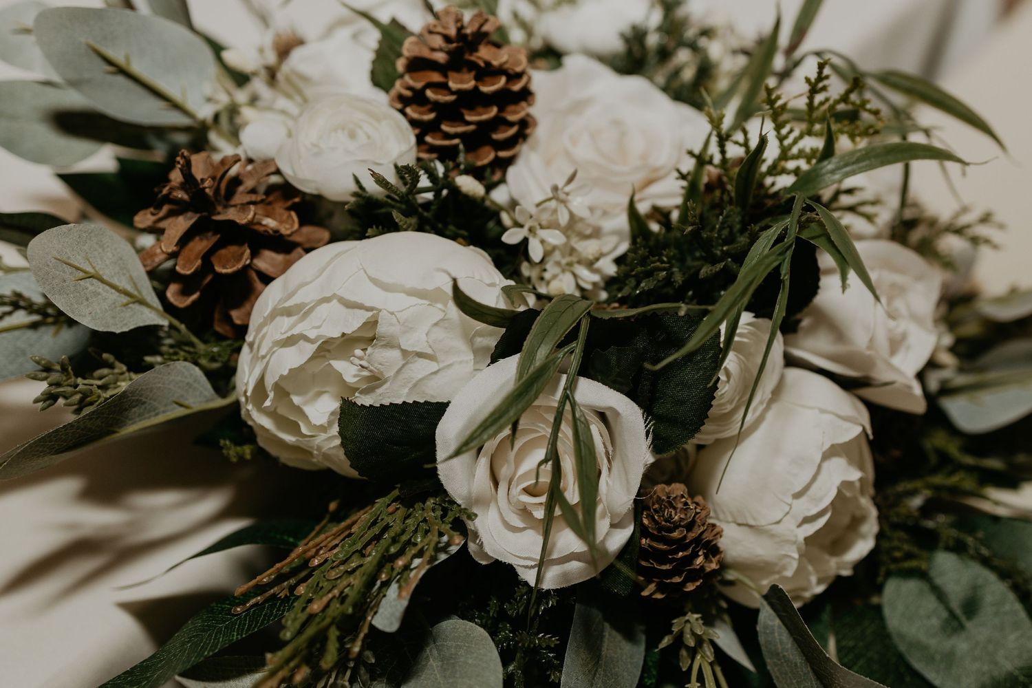 Wedding flowers with pinecones and greenery in a rustic winter arrangement.