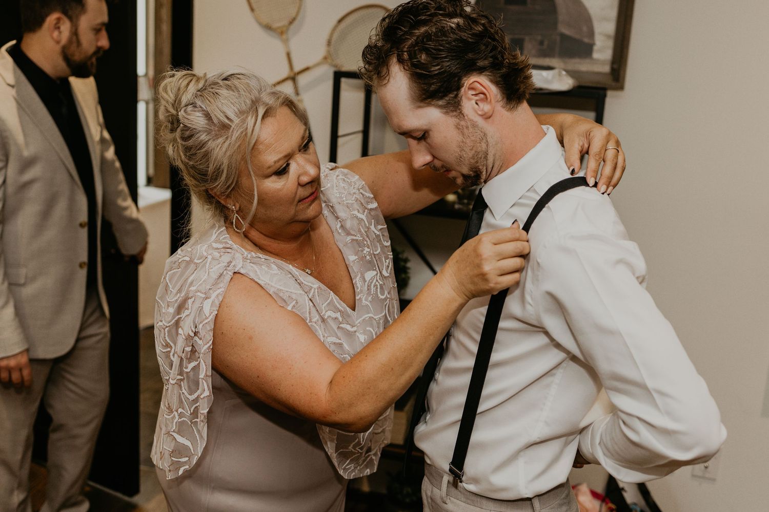 A touching moment of helping adjust formal attire during wedding preparations.