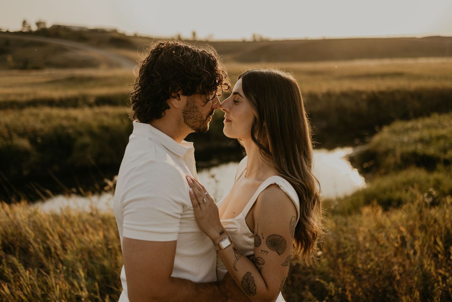 Romantic golden hour portrait in a rural field with warm sunlight creating a dreamy atmosphere.
