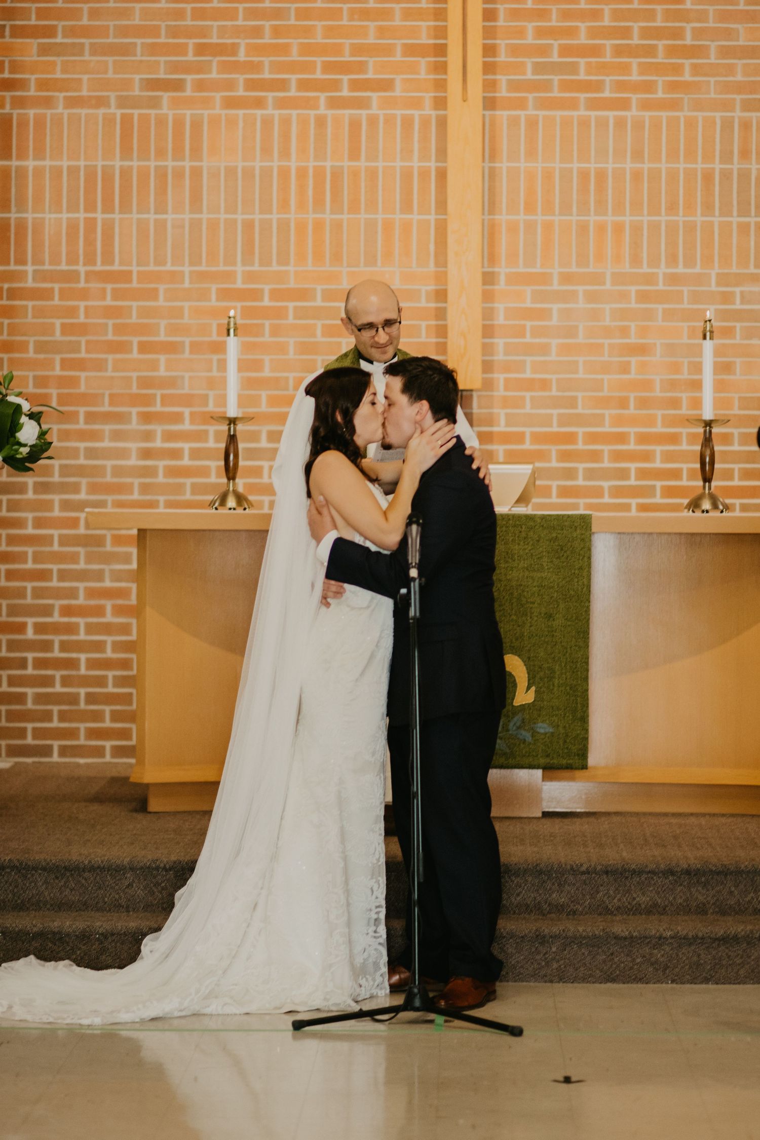 Traditional church wedding ceremony with couple sharing first kiss at altar.