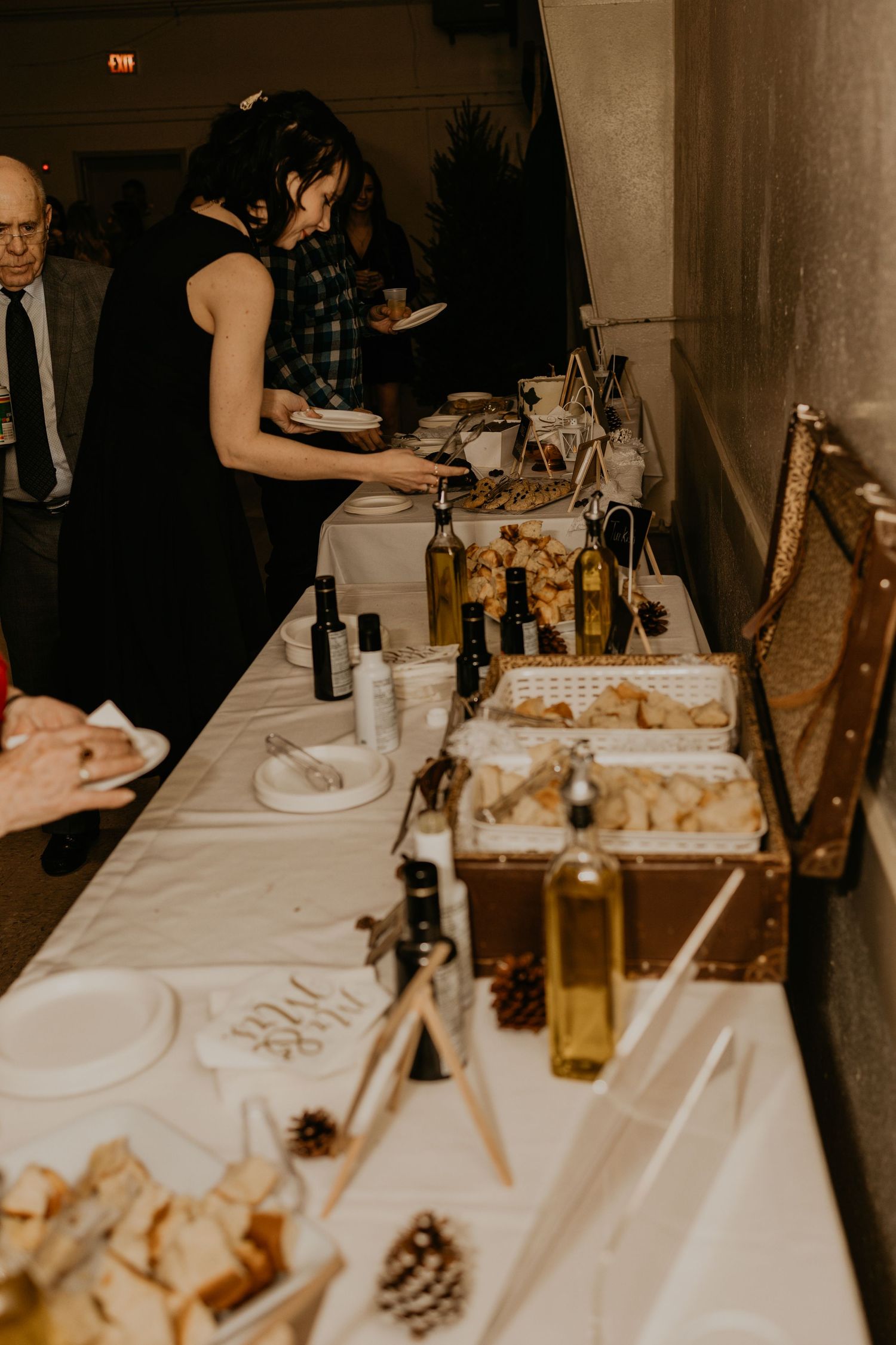 Wedding buffet table with various dishes and wine bottles arranged on white tablecloth.