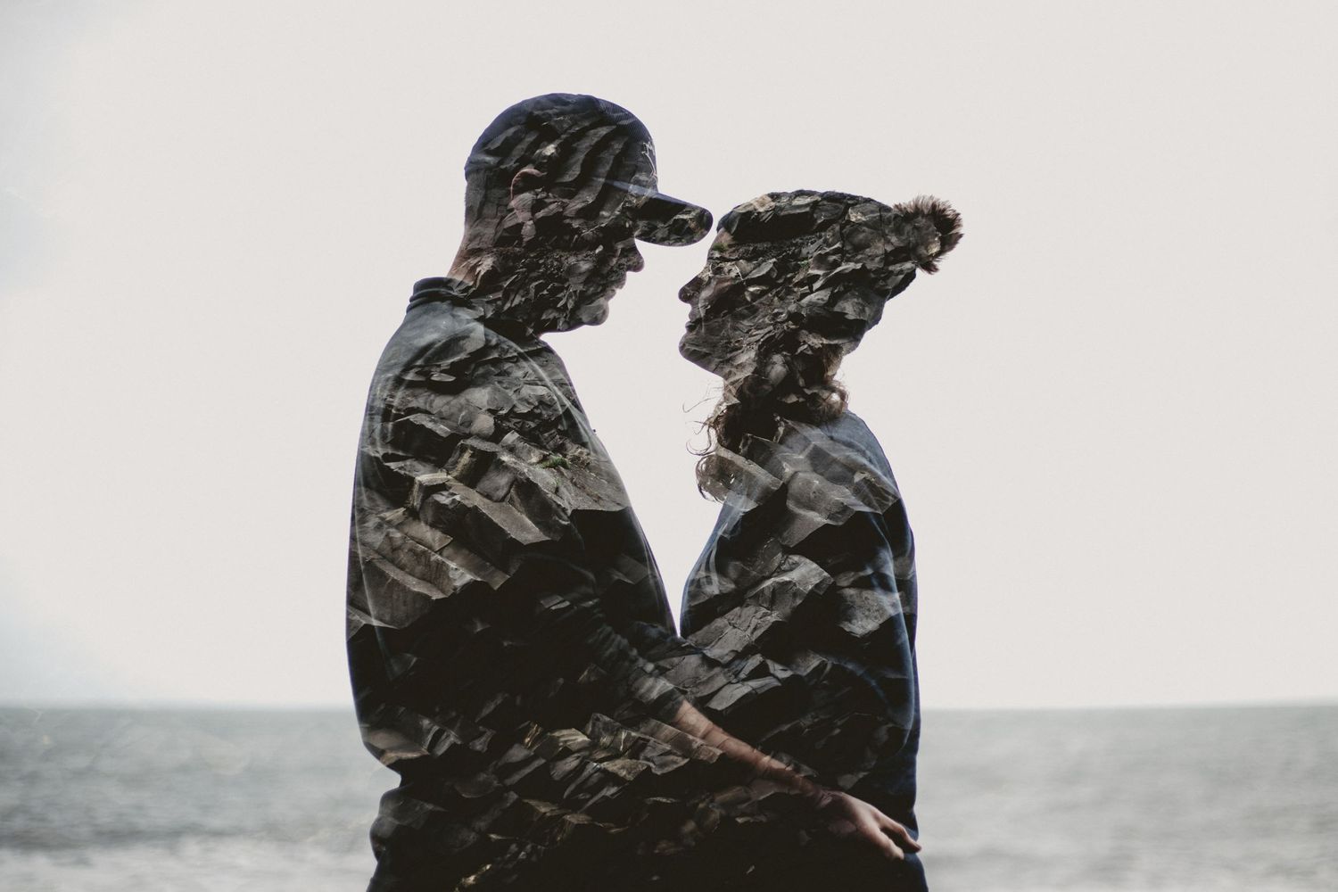 Artistic double exposure silhouette of a couple against an ocean backdrop with textured overlay.