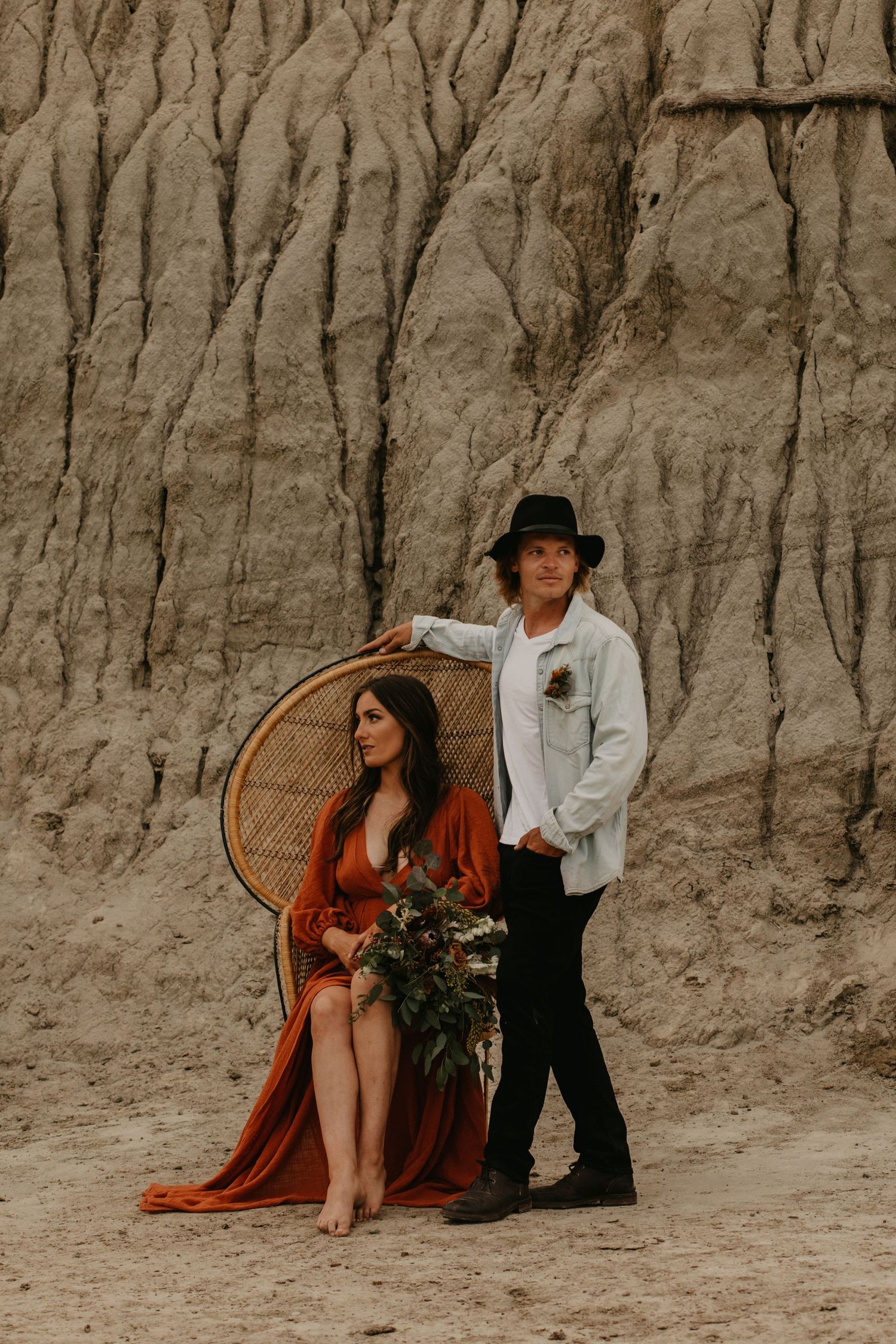 A stylish desert photoshoot featuring a peacock chair and rust-colored dress.