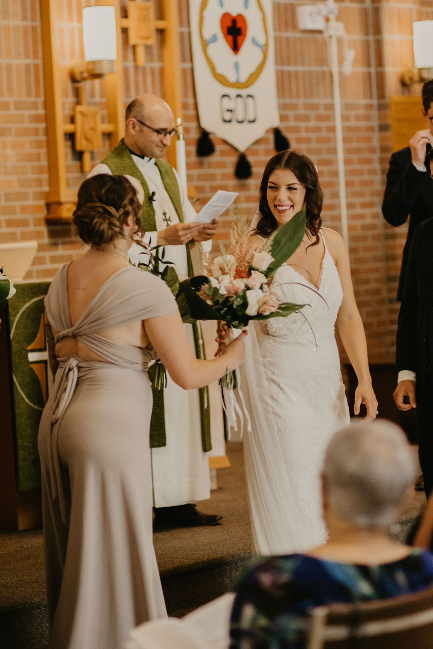 A wedding ceremony moment with attendants and clergy in a church with decorative banners.