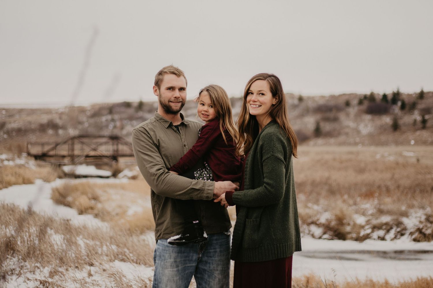 Casual family portrait in a winter field with muted tones and natural lighting.