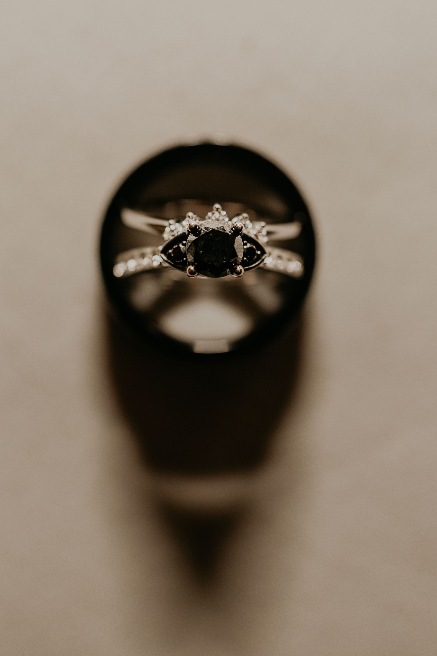 Elegant engagement ring with black center stone and diamond accents photographed in dramatic lighting.