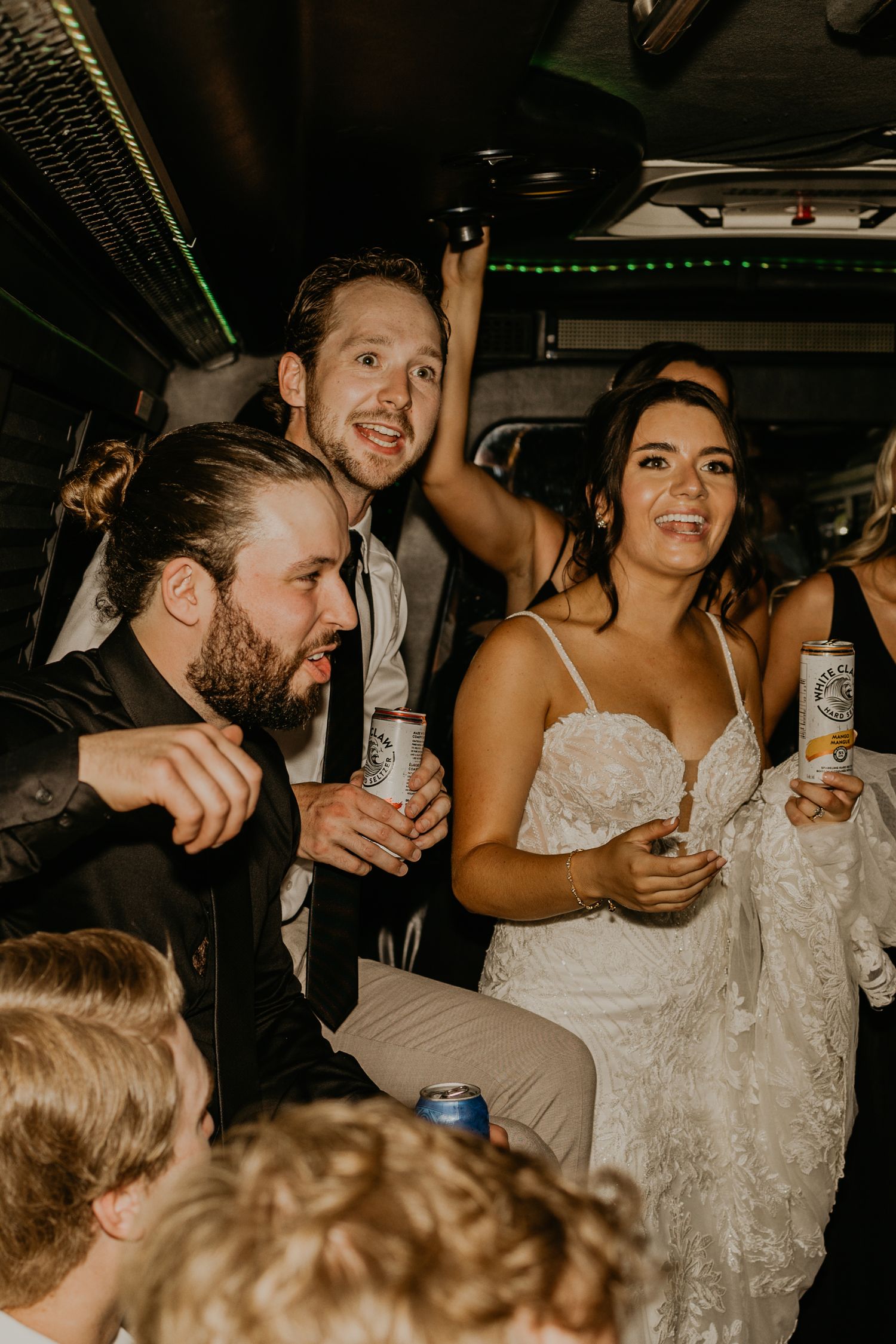 Wedding celebration continues on party bus with drinks and dancing.